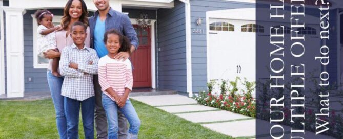 Smiling family of 5 standing in front of a new gray 2 story home